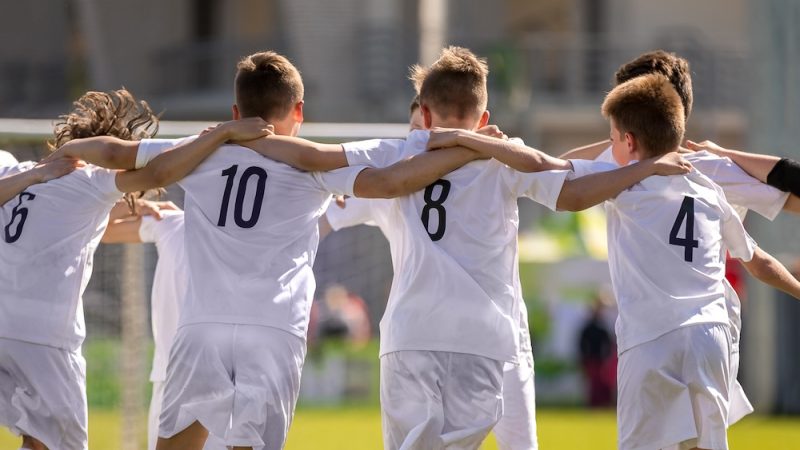 Happy Soccer Players. Happy Boys Winning Soccer Match. Young Successful Soccer Football Players Dancing Together on the Pitch.