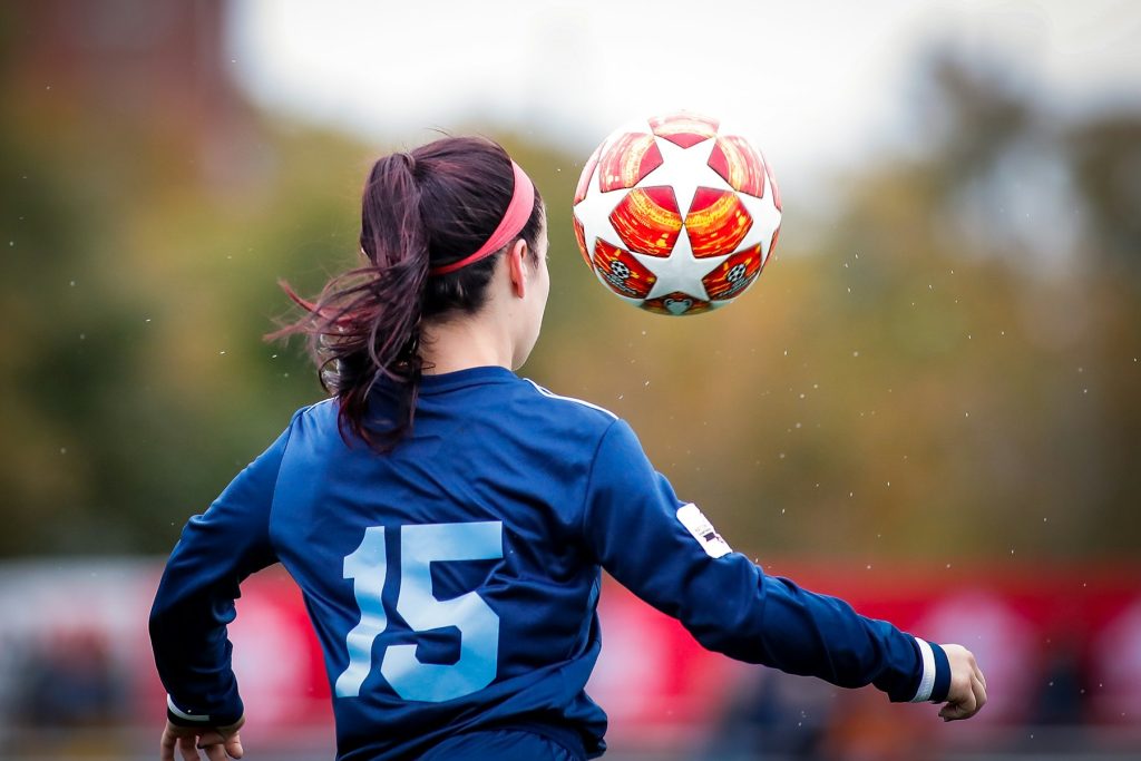 Girl soccer player in a blue jersey controlling the ball during a game