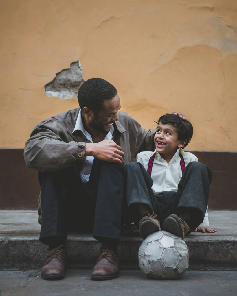Father and son sitting together, a reminder that parent support helps a young athlete’s mental health