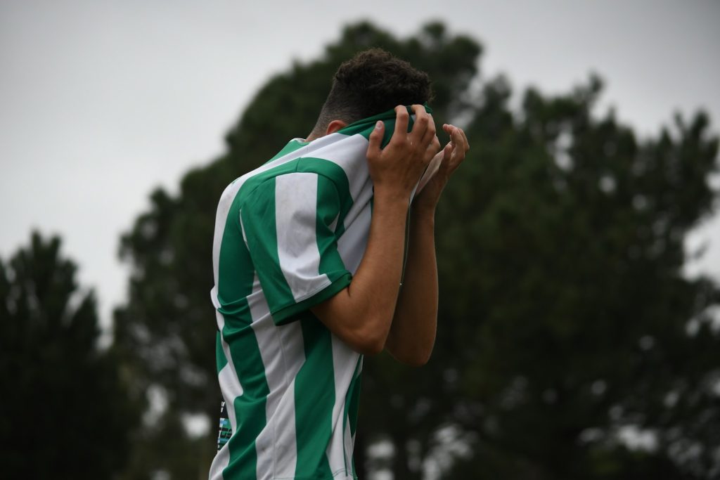 Soccer player covering his face, showing the mental health toll of a sports injury