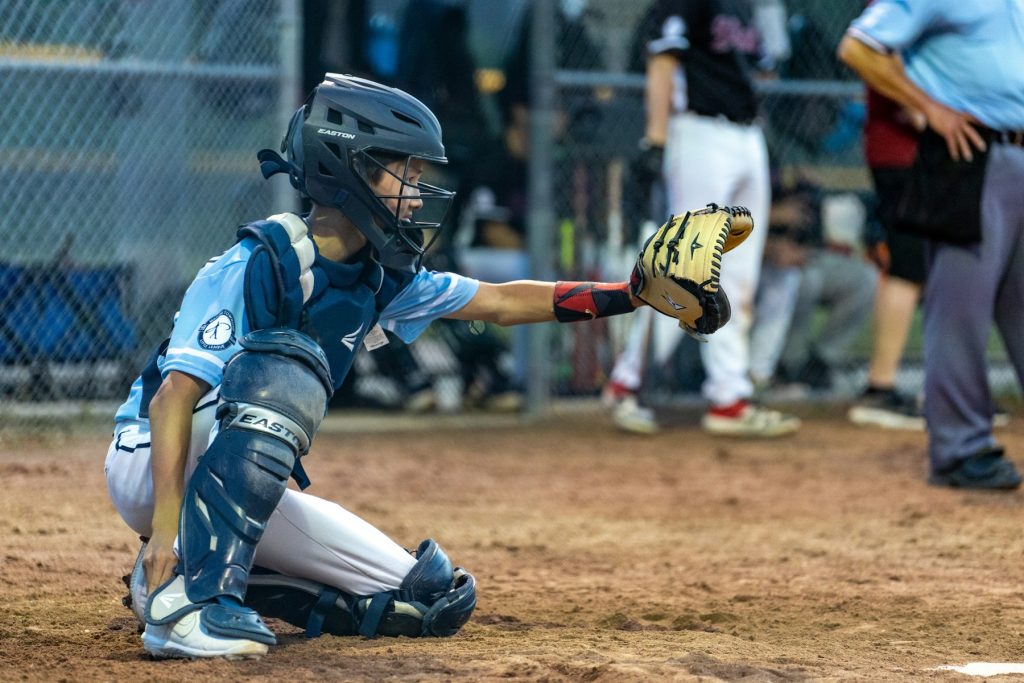 Young catcher in full gear reaching for a pitch behind home plate