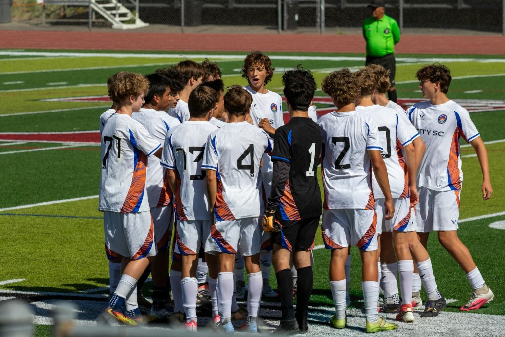 Youth soccer team huddled together, a source of mental health support for injured teammates